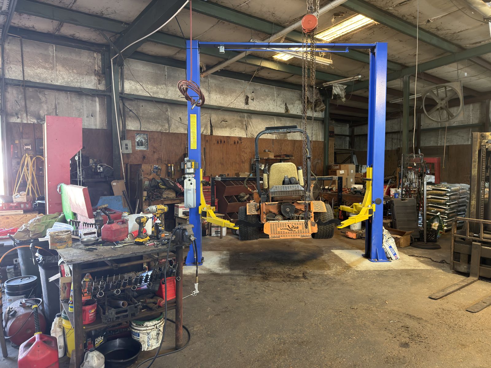 Zero-turn mower on a hydraulic lift in the Feeders Milling equipment service shop